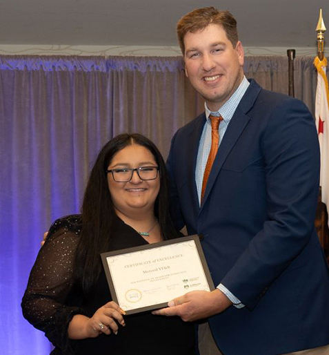 The Merced Young Farmers & Ranchers Committee, represented by Sariah Avila, left, receives the YF&R award for community involvement from Daniel Jones, YF&R State Committee chair.